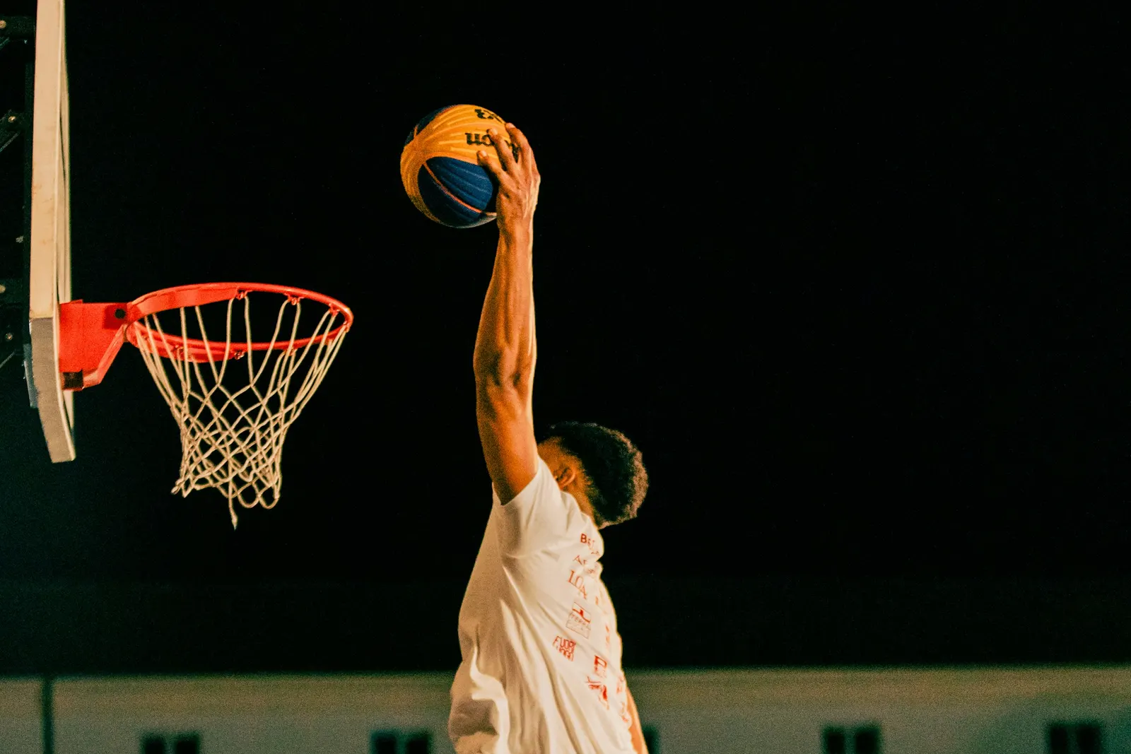 Joueur de basket suspendu en plein dunk de nuit